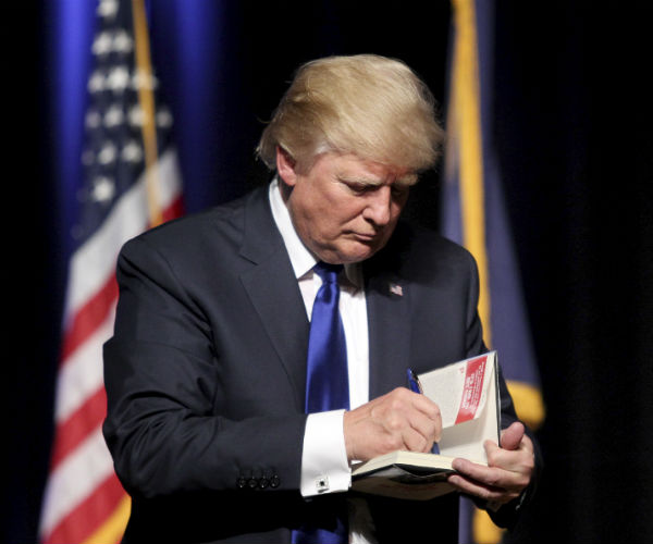 Then-Republican presidential candidate businessman Donald Trump signs a copy of his book "Trump: The Art of the Deal" at the conclusion of his campaign town hall event, back on Aug. 19, 2015, at Pinkerton Academy in Derry, N.H. (Mary Schwalm/AP)